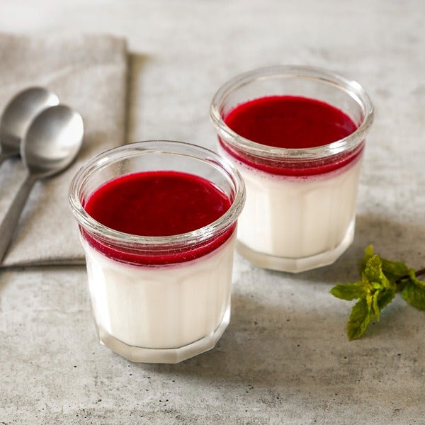 Photo culinaire Del Arte de panna cotta au coulis rouge, illustration du dessert crémeux aux fruits rouges ; présentation indicative.
